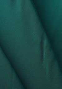 Tissu vert présentant une texture lisse avec un léger éclat, doté de plis et de drapés qui mettent en valeur son matériau doux et flexible.