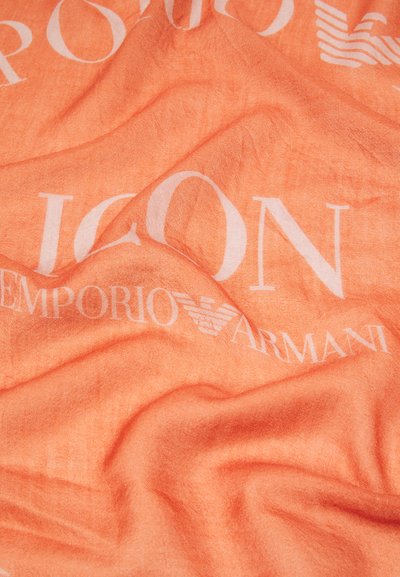 Persikofärgad-orange tyg med en mjuk textur, prydd med stora vita bokstäver som säger "ICON EMPORIO ARMANI" tillsammans med en logotyp.