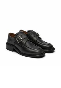 Scarpe in pelle nera con doppia fascia e dettagli in fibbia, caratterizzate da punta arrotondata e accenti brogue, montate su un tacco basso e impilato.