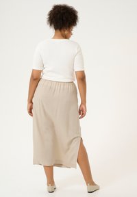 Maxiskirt i beige, lavet af letvægtsstof med elastisk talje og en sideslids. Sammen med en hvid tætsiddende kortærmet top.