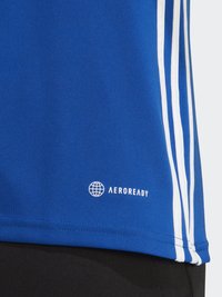 Kék sportpóló, fehér csíkokkal az oldalán. Az alján fehér színben megjelenő "AEROREADY" logóval. Sima tapintású.