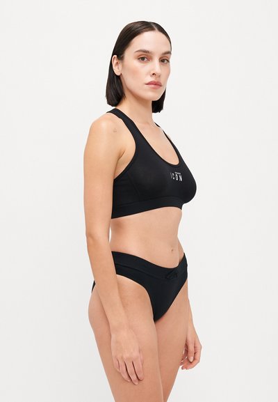 Black sports bra and bikini set featuring a smooth fabric, wide adjustable straps, and a subtle logo on the bra.