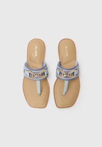 Sandali blu chiaro con un accento circolare dorato, punta squadrata e una suola liscia color tan. La cinghia è realizzata con un tessuto decorato.