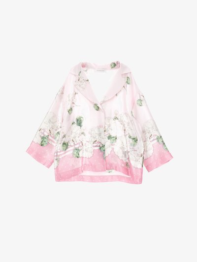 Měkká růžová hedvábná blůza s bílým květinovým potiskem, širokým límcem, dlouhými rukávy a růžovým lemem s puntíky na spodním okraji a manžetách.