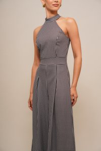 Sukienka w wzór houndstooth, bez ramiączek, z wysokim kołnierzem, dopasowanym gorsetem i zwiewnym dołem, w kolorach czarnym i białym, o gładkiej teksturze materiału.