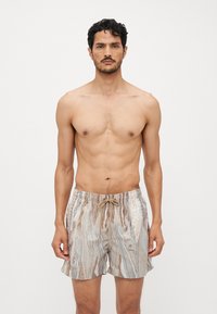 Shorts de bain fabriqués dans un tissu léger et texturé, arborant un motif coloré et abstrait de peau de serpent, avec une taille élastique et un cordon de serrage.