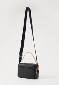 Black leather crossbody bag with gold-tone chain accents, rounded rectangular shape, zip closure, and adjustable strap. Textured surface.