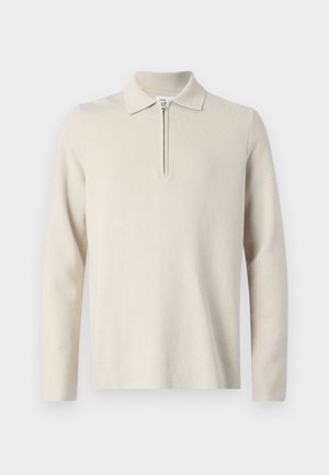 Krém színű, hosszú ujjú pólóing, nyakán cipzárral, puha, texturált anyagból, klasszikus fazonban és minimalista stílusban.