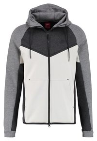 Gray and white zip-up hoodie with a hood, made of soft fabric. Features contrasting sleeves, a chevron design, and front pockets.