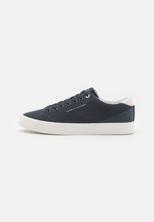 Low-Top Tommy Hilfiger Sneaker in Marineblau mit weißer Sohle, weißem Fersenlasche und gebrandetem Schriftzug an der Seite, von der Außenseite gezeigt.