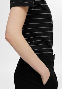 Schwarz-weiß gestreiftes kurzärmliges Oberteil mit rundem Ausschnitt und slim fit, kombiniert mit schwarzen, strukturierten Hosen mit hoher Taille.