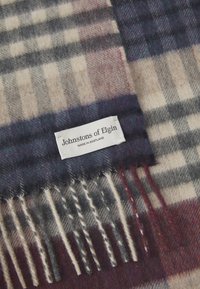 Wool scarf featuring a grey and beige plaid pattern with fringed edges; label reads "Johnstons of Elgin, Made in Scotland."
