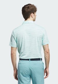 Polo shirt azzurro chiaro a maniche corte con un motivo testurizzato. Il design con colletto e le strisce sottili creano un look moderno. Abbinato a pantaloni coordinati.
