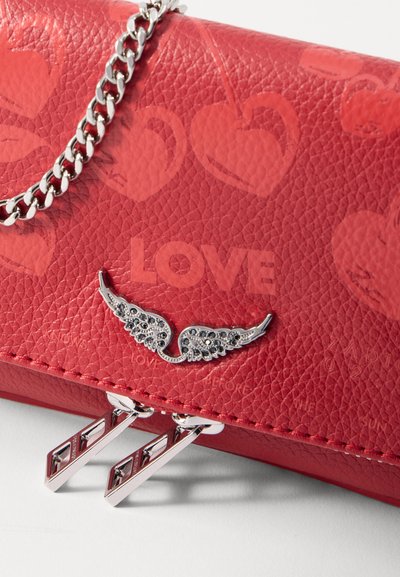 Pochette en simili cuir rouge avec un motif de cœur en relief, accent en métal argenté en forme d'aile, chaîne en bandoulière et quincaillerie métallique pour la fermeture.
