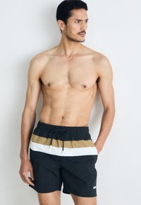 Schwarze Schwimmshorts mit horizontalen Streifen in Weiß und Beige. Elastischer Taillenbund mit Kordelzug, glatte Textur, Oberschenkel-lange.