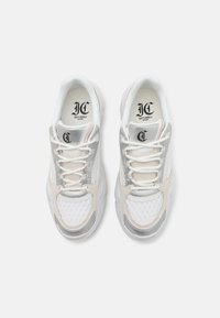 White and silver sneakers feature a mesh and suede upper, round toe, lace-up closure, and embossed logo on the tongue. Thick, textured soles.