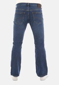 Blauwe denim jeans met een uitlopende pijpdesign, voorzien van een bruin leren tailleband tag en twee achterzakken met gebogen stiksels.