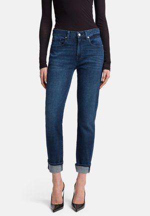 Jean en denim bleu foncé avec une coupe ajustée, ourlets roulés, cinq poches et une légère élasticité pour un confort optimal. Équipé d'une fermeture à boutons et à glissière en argent.