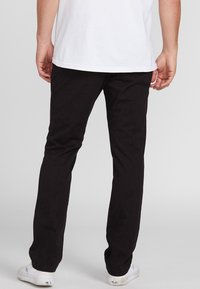 Zwarte broek in een aansluitend ontwerp, met een gladde textuur, tailormade snit en een lichte stretch, gecombineerd met witte sneakers.