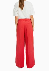 Weite Hosen aus leuchtend rotem Leinen mit einer Faltendetail vorne und einem gesicherten Bund. Verfügt über eine Gesäßtasche auf der rechten Seite.