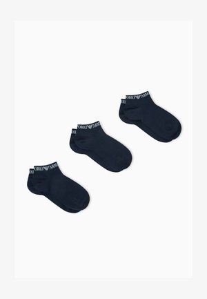 Tre paia di calzini neri alla caviglia con il marchio bianco "Emporio Armani" sui polsini, disposti su uno sfondo bianco.