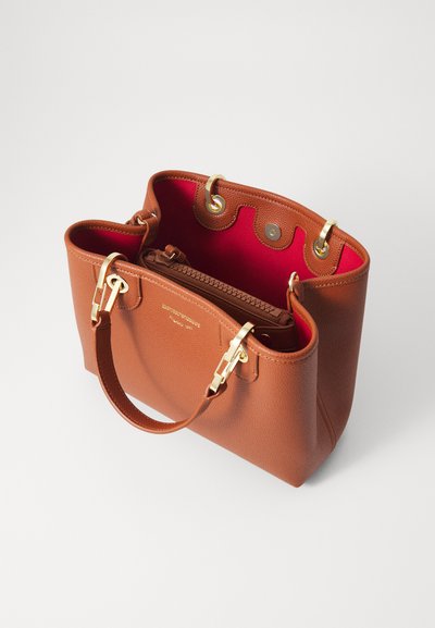 Sac à main en cuir tan avec des accessoires en or, ouverture sur le dessus et intérieur rouge. Comprend des fermetures à pression sur le côté et un petit compartiment zippé à l'intérieur.