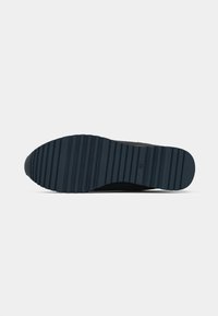 Semelle de sneaker noire avec des rainures horizontales pour une traction, taille 40 marquée près du talon, présentée sur un fond blanc uni.