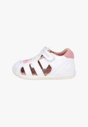 Sandalia de cuero blanca con diseño recortado, acentos en rosa y un gráfico divertido de una nube sonriente. Cuenta con una correa ajustable para un ajuste seguro.