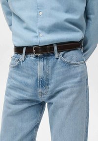 Vaqueros de mezclilla azul claro con textura desgastada, combinados con una camisa abotonada azul claro y un elegante cinturón de cuero negro.