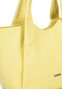 Bolso de cuero amarillo con una superficie texturizada, asas dobles y un pequeño logo plateado. Forma redondeada y detalles de costura visibles.
