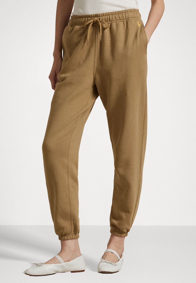 Braune Baumwoll-Jogginghosen mit elastischem Bund, Kordelzug, Seitentaschen und schmal zulaufenden Bündchen. Ausgestattet mit einem kleinen Logo auf der linken Seite.