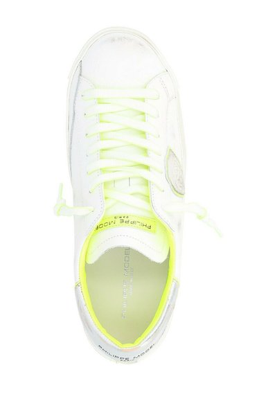 Sneaker bianco con accenti giallo neon, caratterizzato da lacci testurizzati, una superficie liscia e un logo sul lato. Elementi di design accattivanti.