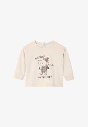 Light beige long-sleeve shirt made of soft fabric featuring a cartoon character with a backpack and text "QUELLE BELLE AVENTURE!"