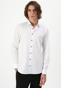 Weißes Langarmhemd aus glatter Baumwolle. Mit einem Button-Down-Kragen und dunklen Knöpfen, taillierter Schnitt und einfachem Design.