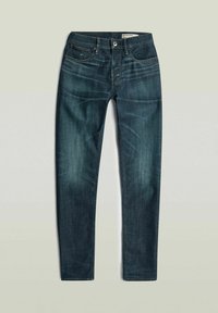 Jean slim bleu foncé avec légère décoloration, passants pour ceinture, fermeture par bouton, et cinq poches, posé à plat sur un fond uni.