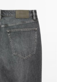 Mörkgrå denimjeans med en märkesläderpatch baktill, klassisk femfickorsdesign och subtila blekningsdetaljer.