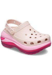 Zuecos Crocs en color rosa y crema con agujeros cortados y una correa en el talón, que presentan una parte superior texturizada y una suela acolchada en rosa y púrpura.