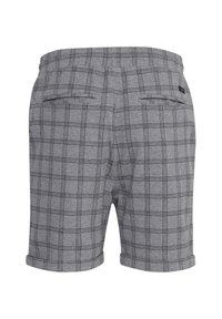 Shorts à carreaux gris avec une texture douce, présentant des lignes de grille noires, deux poches arrière et des ourlets retroussés pour un look décontracté.