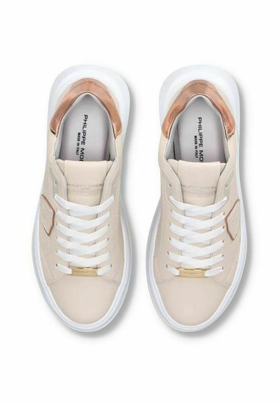 Beige lædersneakers med hvide såler, gyldne accenter og hvide snørebånd. Har en metal hældetalje og en struktureret sidepanel.