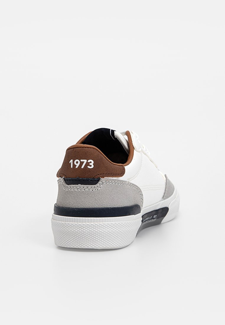 Zapatillas para hombre con parte superior de cuero blanco, talón de ante marrón, detalles grises, cuello acolchado y suela de goma texturizada; presenta "1973" en blanco en el talón.