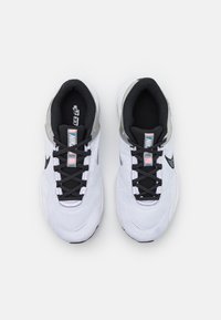 Białe buty sportowe z czarnymi sznurowadłami i podszyciem, wyróżniające się srebrnym akcentem i teksturowanym materiałem siateczkowym, z logo na języku.