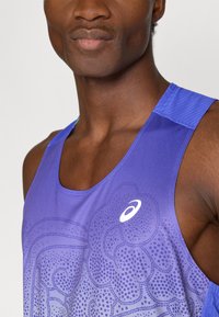 Μωβ αθλητική μπλούζα με σχέδιο γκράντ, με στρογγυλή λαιμόκοψη και υφασμάτινες τιράντες. Λογότυπο εμφανίζεται στο στήθος.