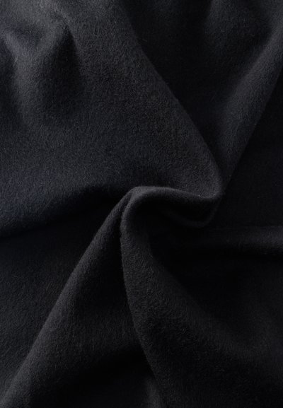 Puha fekete anyag bolyhos textúrával, közelről bemutatva gyengéd redőkkel és enyhe gyűrődésekkel.