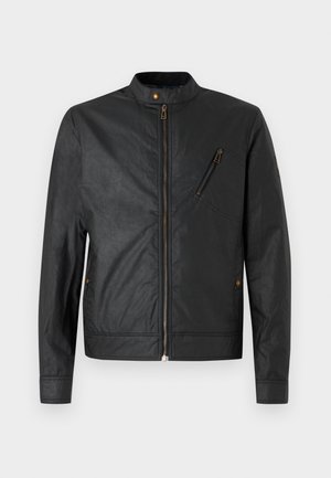 Svart jakke laget av teksturert stoff med stående krage, glidelås og skrå lomme, med bronsefargede detaljer.