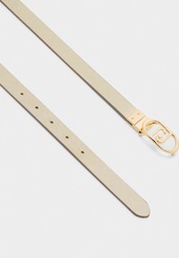 Beżowy pasek z teksturą z metalową złotą klamrą, z dekoracyjnym logo. Posiada kilka otworów do regulacji na pasku.