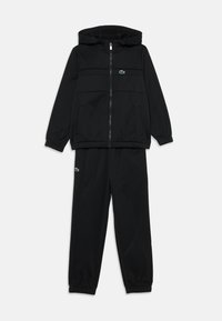 Survêtement noir comprenant un hoodie zippé avec une poche kangourou et un pantalon assorti. Les deux sont dotés de poignets élastiques et d'un petit accent logo vert.