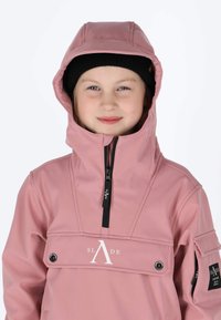 Roze waterdichte jas met hoge kraag en rits aan de voorkant. Heeft een logo op de borst, een verstelbare capuchon en een zak op de mouw.