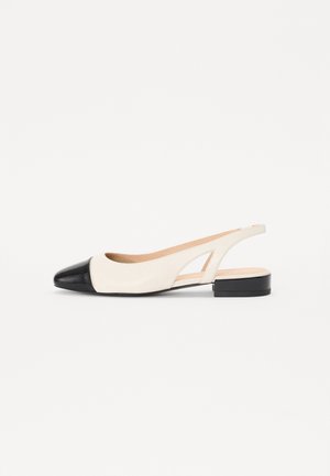 Sandały typu slingback w kremowej skórze z czarnym lakierowanym czubkiem. Posiadają niski blokowy obcas i wycięcia po bokach dla lepszej wentylacji.