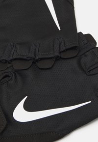 Black Nike gloves with a textured fabric, featuring a prominent white swoosh logo and finger openings for enhanced grip.