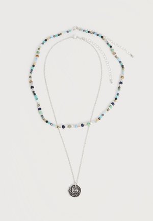 Collier double couche avec chaîne en argent et pendentif, ainsi que de petites perles multicolores sur la couche supérieure avec fermoirs réglables.